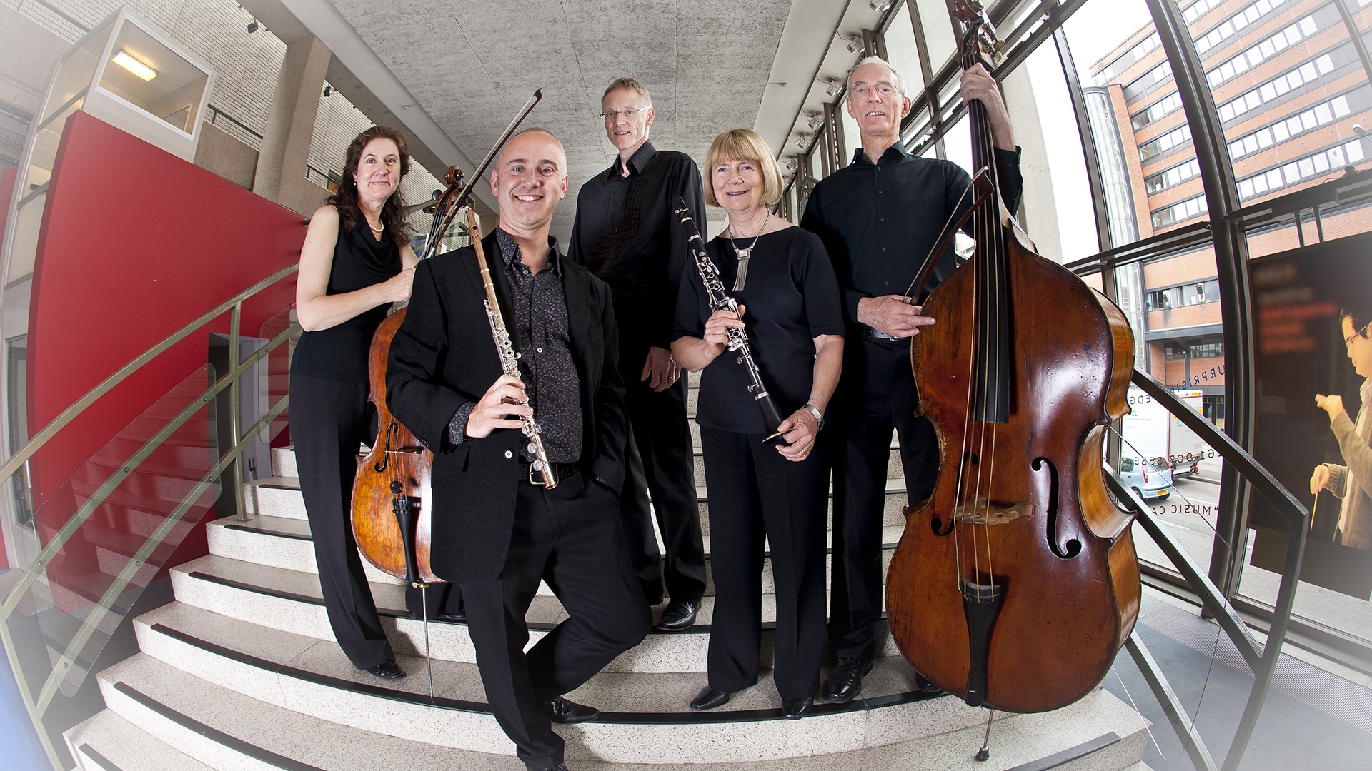 The Pleyel Ensemble, a group of 5 people dressed in smart black clothes, holding wind and string instruments.